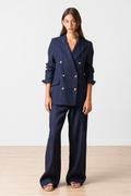 Woman wearing a navy blue linen suit with tortoise buttons on a white background