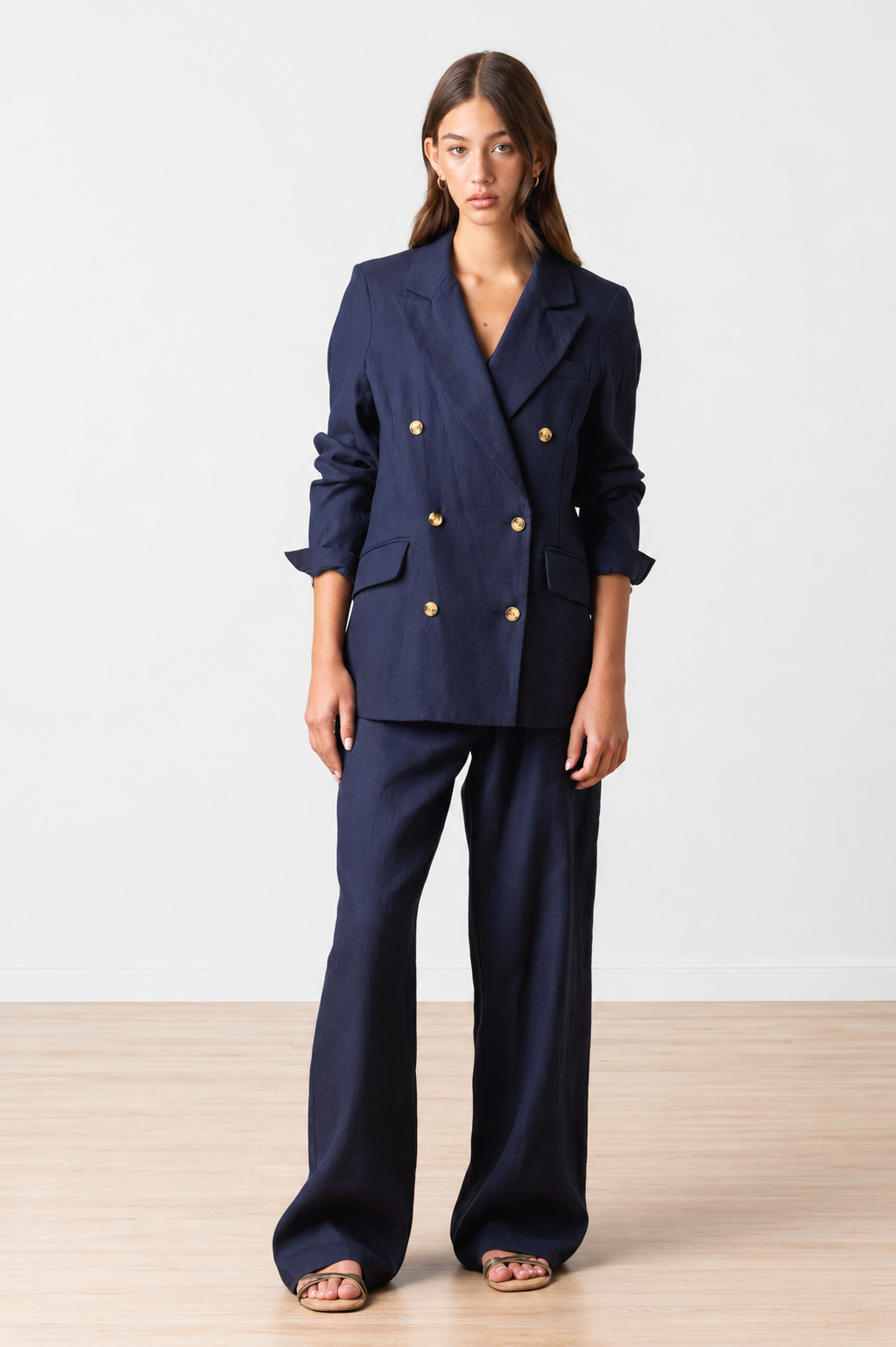 Woman wearing a navy blue suit with tortoise buttons on a white background
