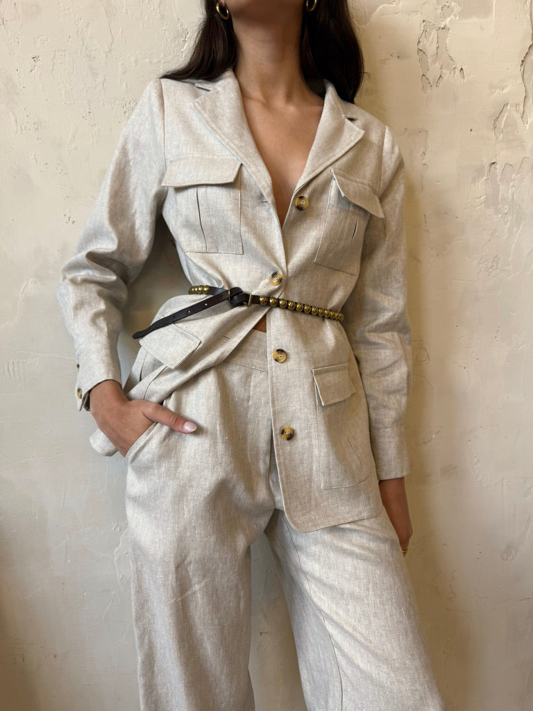 Woman wearing a Whitney Linen safari jacket styled with relaxed herringbone 
linen trousers.